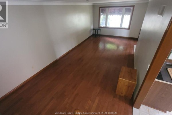 Living room with polished hardwood floors, neutral walls, and a large window. - 1058 Riverdale, Windsor