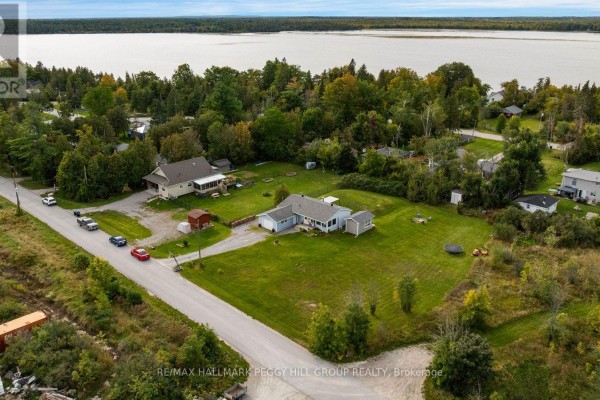 Aerial view of house with large green lawn, surrounded by trees and lake. - 1058 Sunrise Drive, Ramara