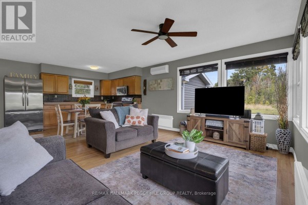 Living room with sofa, TV, and view into kitchen with wooden cabinets. - 1058 Sunrise Drive, Ramara