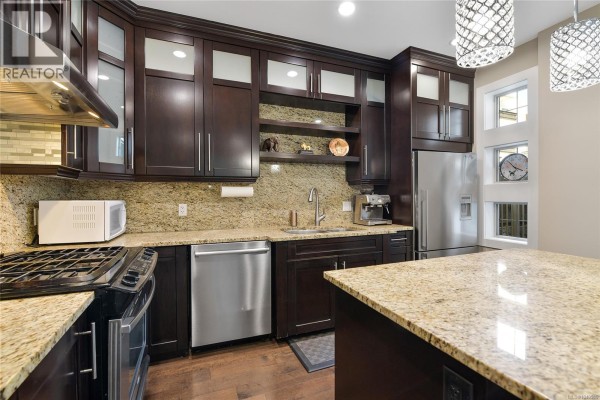 Modern kitchen with dark wood cabinets, granite countertops, stainless steel appliances, and an island. - 1059 Clare St, Victoria