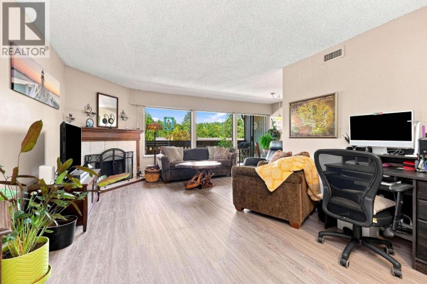 Living room with fireplace, television, large windows, and neutral-colored furniture. - 1059 Old Lillooet Road, North Vancouver