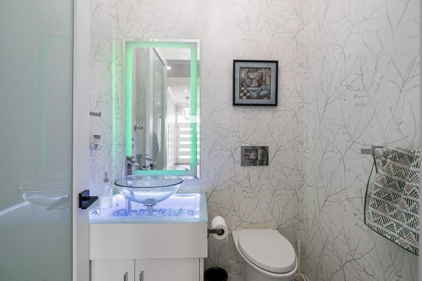 Powder room with a glass bowl sink, white toilet, and decorative wallpaper. - 10598 124 Street, Surrey