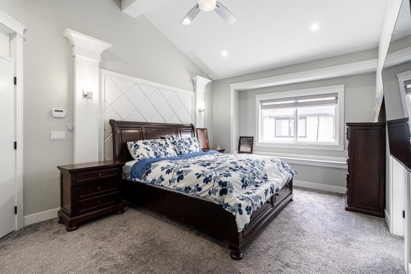 Bedroom with a king-size bed, dark wood furniture, and a large window seat. - 10598 124 Street, Surrey