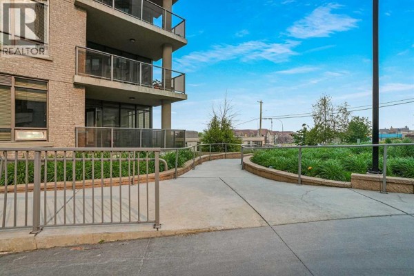 Pathway leading to an apartment building with balconies and a grassy area. - 106, 10 Shawnee Hill Sw, Calgary