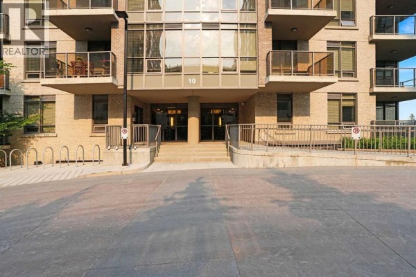 Front entrance of a brick apartment building with stairs and a ramp. - 106, 10 Shawnee Hill Sw, Calgary