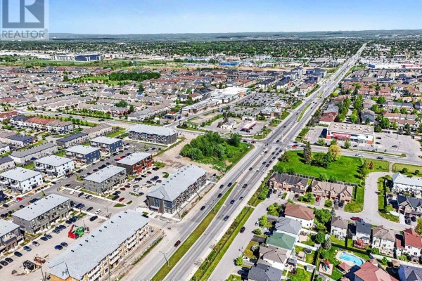 Aerial view of a suburban area with low-rise apartment buildings and a busy commercial street. - 106 - 2370 Tenth Line Road, Ottawa