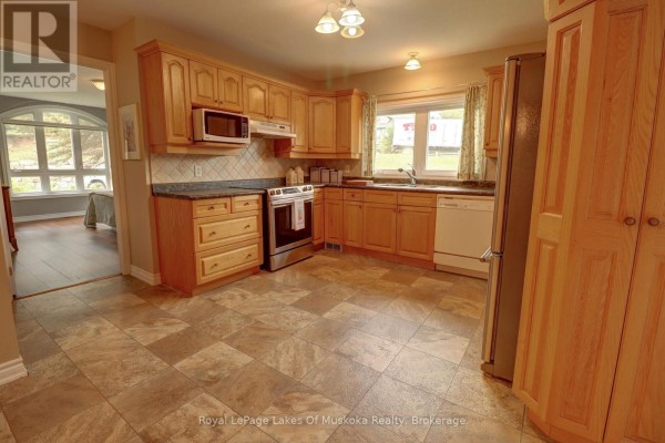 View of the kitchen opening to a living area with arched doorway and large window. - 106 - 31 Dairy Lane, Huntsville