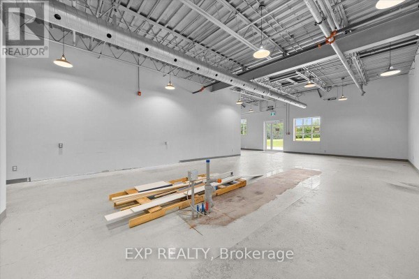 Wide view of interior commercial space with white walls, exposed metal ceiling, and large glass doors showing greenery outside. - 106 - 40 Sunset Boulevard, Perth