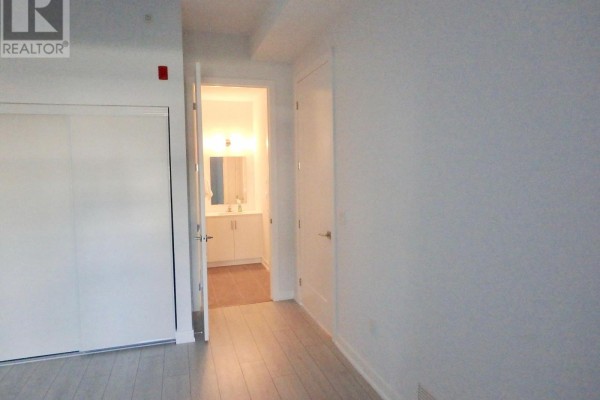 Hallway with wood floors, sliding closet, and bathroom with vanity and mirror - 106 - 4040 Upper Middle Road, Burlington