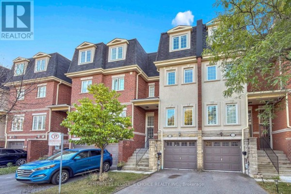 Front exterior of a multi-story townhouse with brick and light beige siding and garages. - 106 - 435 Hensall Circle, Mississauga