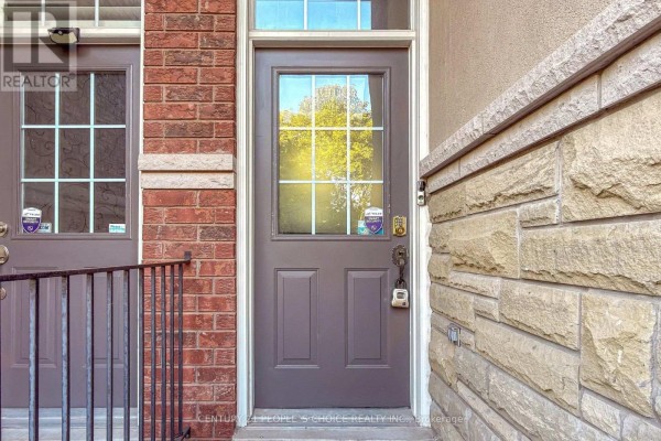 Close-up of a brown front door with a glass pane, flanked by brick and stone siding. - 106 - 435 Hensall Circle, Mississauga