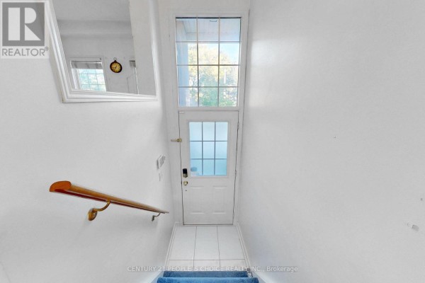 Interior view of a white entryway with a door, mirror, and blue carpeted stairs. - 106 - 435 Hensall Circle, Mississauga