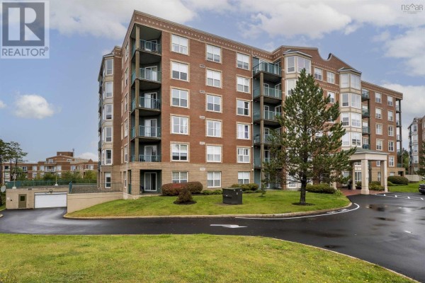 Side view of a red brick apartment building with balconies and surrounding green lawn. - 106 - 78 Regency Park Drive, Clayton Park