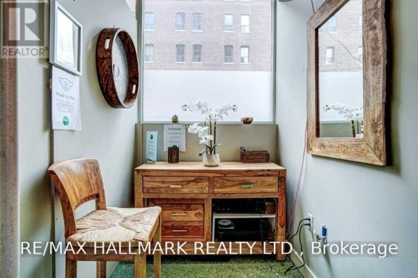 A small reception area with a wooden chair, desk, and a frosted window overlooking buildings. - 106 - 80 Sherbourne Street, Toronto
