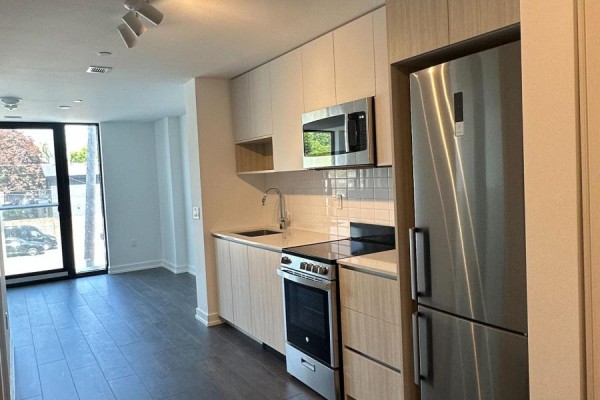 Modern kitchen with light wood cabinets, stainless steel appliances, and a gas range. - 106 - 801 The Queensway, Toronto