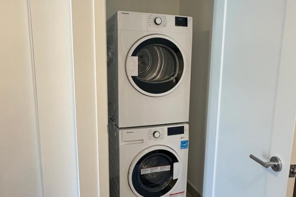 Stackable white washer and dryer unit inside a closet with white doors. - 106 - 801 The Queensway, Toronto