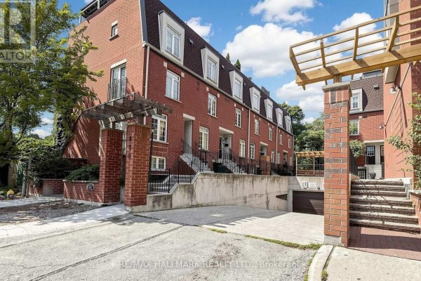 Entrance to the townhouse complex showing brick pillars, wooden pergola, and underground parking. - 106 - 870 Jane Street, Toronto