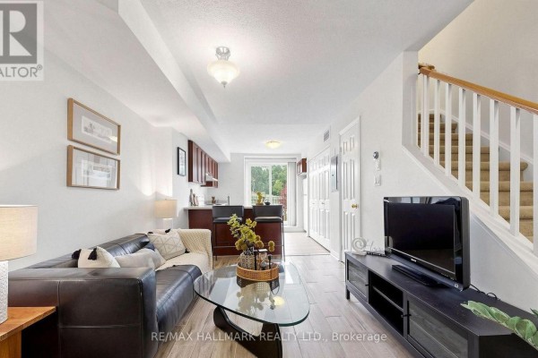 Open concept living area with kitchen, sofa, glass coffee table, and stairs to upper level. - 106 - 870 Jane Street, Toronto