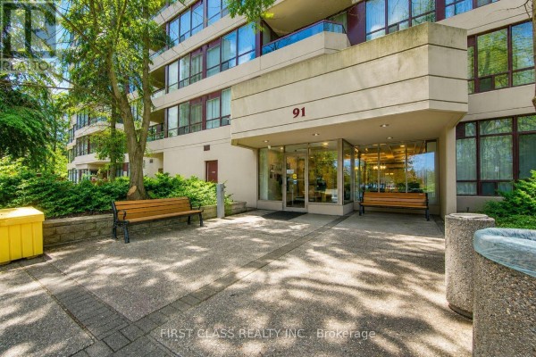 Entrance to apartment building 91 with glass doors, benches, and shrubs. - 106 - 91 Townsgate Drive, Vaughan
