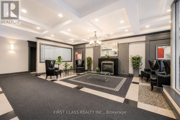Apartment building lobby with fireplace, seating area, and patterned carpet. - 106 - 91 Townsgate Drive, Vaughan