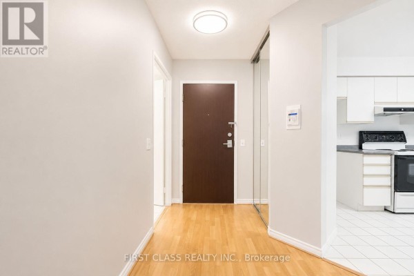 Interior entryway with hardwood floor, dark door, and mirrored closet. - 106 - 91 Townsgate Drive, Vaughan
