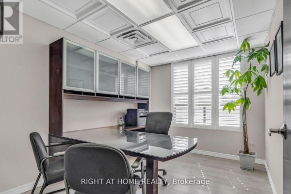 Reception desk with glass top and dark wood base, facing an office space. - 106 - 99 Holland Avenue, Ottawa
