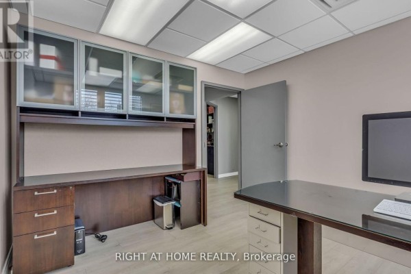 Office hallway with gray walls, blue accent wall with art, chairs, and closed doors. - 106 - 99 Holland Avenue, Ottawa