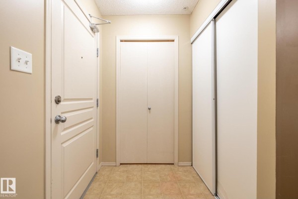 Apartment hallway with two closets and a cream-colored door. - #106 1188 Hyndman Rd Nw, Edmonton