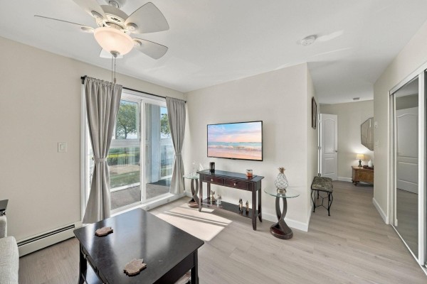 Living room with a sofa, television, entryway, and view of the kitchen area. - 106 14881 Marine Drive, White Rock