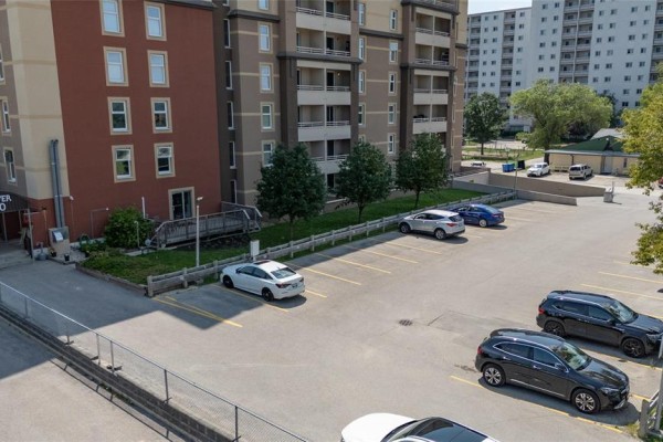 Aerial view of the apartment building's paved parking lot with several cars parked. - 106 180 Beliveau Road, Winnipeg