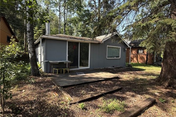 Side view of the grey cottage showing a concrete patio and sliding glass doors. - 106 Agnes Street, Emma Lake