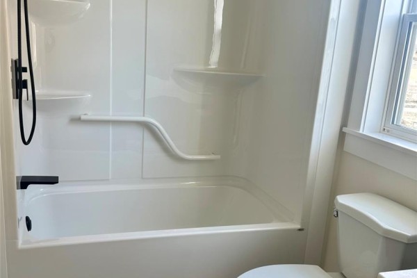 Bedroom with white walls, light wood flooring, and a window facing the street. - 106 Bannock Street, Gander