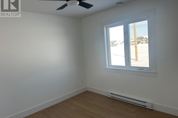 Bedroom with white walls, light wood flooring, and a large bay window. - 106 Bannock Street, Gander
