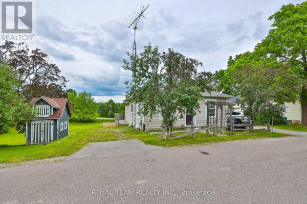 Exterior of a light-colored house with a dark wood outbuilding, wooden pergola, and parked car. - 106 Centre Street, King