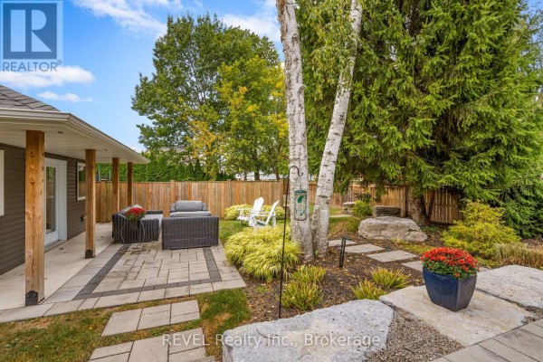 Backyard patio with grey interlocking pavers, dark grey outdoor furniture, and a wooden fence. - 106 Dalhousie Avenue, St  Catharines