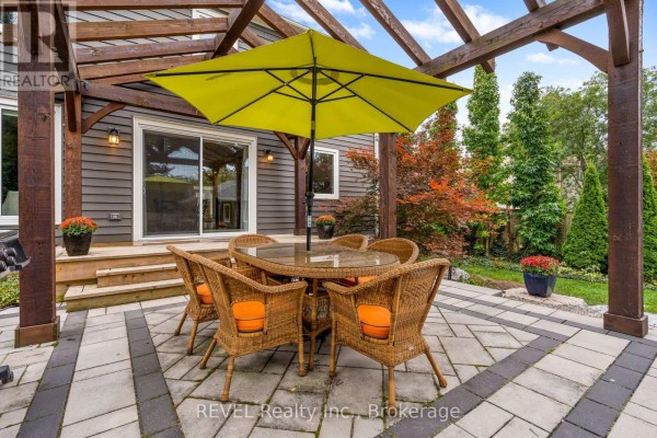 Backyard patio with a wicker dining set, bright yellow umbrella, and a wooden pergola. - 106 Dalhousie Avenue, St  Catharines