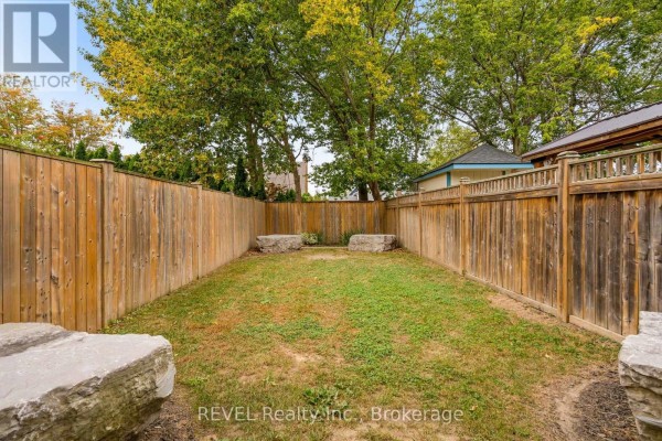 Fully fenced backyard with a grass lawn and large boulder accents on either side. - 106 Dalhousie Avenue, St  Catharines