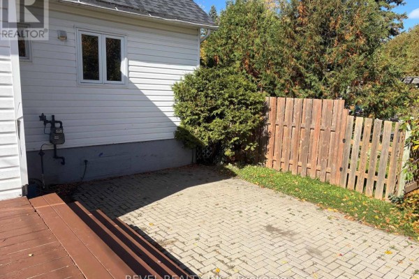Close-up view of the paved patio area and a wooden fence at the rear of the property. - 106 Fifteenth Avenue, Cochrane
