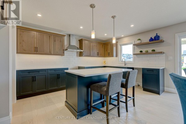 Spacious kitchen featuring a large island with seating, dark blue cabinets, and light wood uppers. - 106 Mapledene Lane, Lucan Biddulph