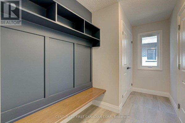 Mudroom with built-in grey storage, a wooden bench, and tiled flooring leading to a hallway. - 106 Mapledene Lane, Lucan Biddulph