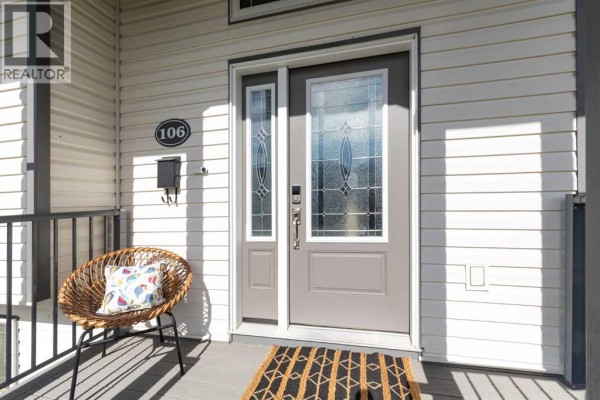 Close-up of the front door entrance with a wicker chair on the porch. - 106 Ranchlands Way Ne, Medicine Hat