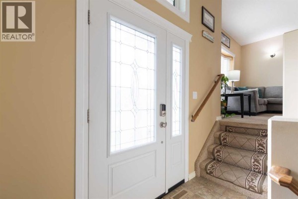 Interior front door with decorative glass panels and stairs leading down to the living area. - 106 Ranchlands Way Ne, Medicine Hat