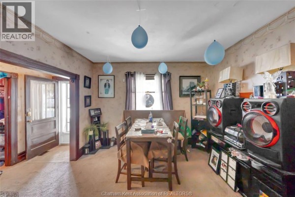 Dining area with a table set for a meal, beige carpet, and sound system on the right. - 106 St. George Street, Chatham