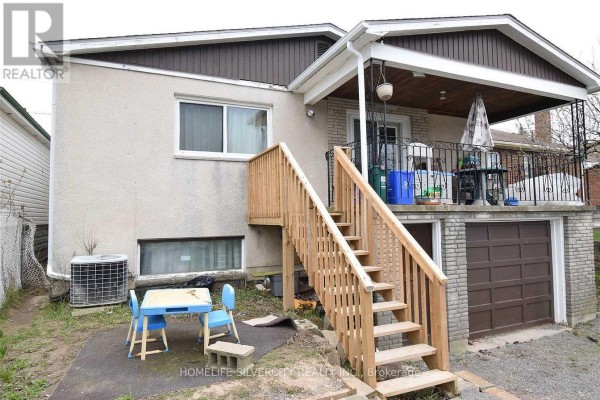 Backyard of the property showing a raised wooden deck, exterior staircase, and attached garage with a concrete driveway. - 106 Townline Road W, St  Catharines