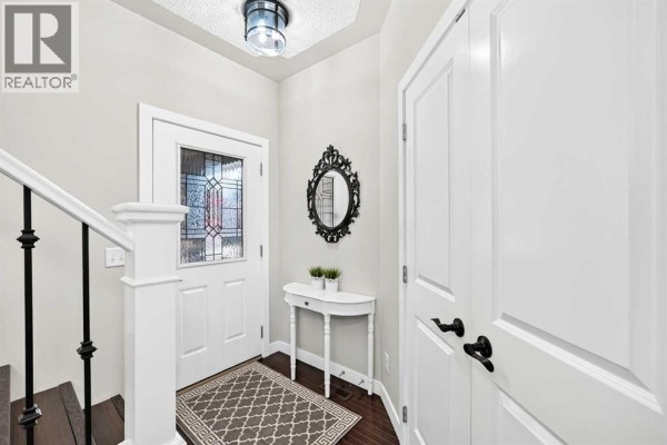Entranceway with a white front door featuring a stained-glass panel and a decorative black mirror. - 1060 Kingston Crescent Se, Airdrie