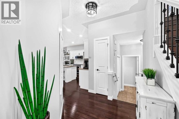 Hallway looking towards the kitchen, featuring dark hardwood floors, white doors, and a decorative chest. - 1060 Kingston Crescent Se, Airdrie