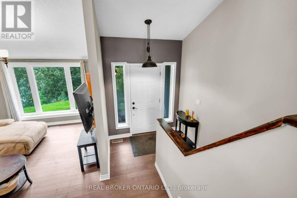 View of the foyer with white door, side windows, and staircase with wooden railing. - 106008 Southgate Rd 10 Line, Southgate