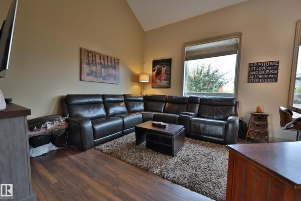 Living room with a large brown leather sectional sofa, coffee table, and beige walls. - 10603 95 St, Morinville
