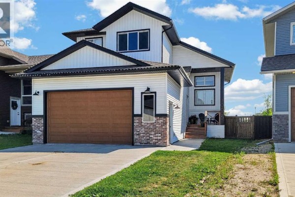 Front exterior of a two-story house with white siding, dark gray trim, and a brown garage door. - 10605 114a Street, Grande Prairie