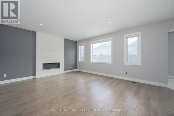 Kitchen island with a sink and marble countertop, open to living room with fireplace. - 1062 Melsetter Way, London North